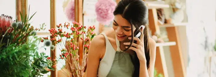Woman smiling while holding mobile phone up to left ear