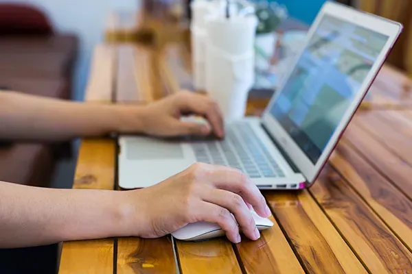 Person typing on laptop while moving mouse