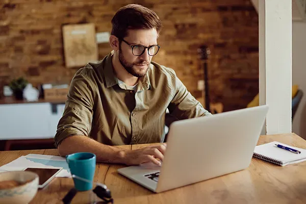 Man with glasses typing on laptop