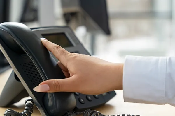 Woman holding telephone down on desk
