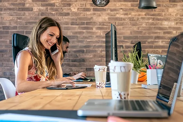 Woman holding phone to left ear in office