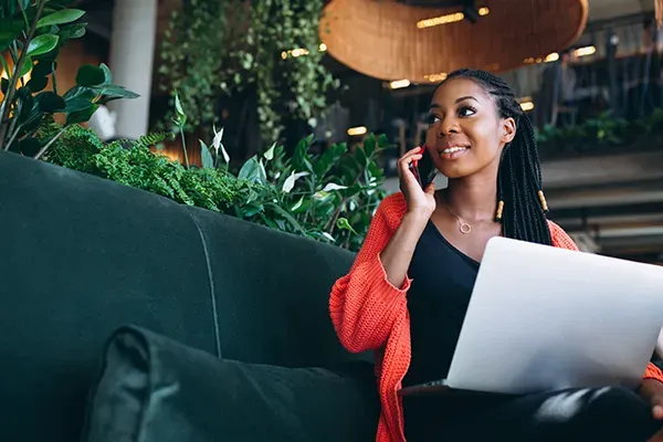 Woman holding phone up to ear with laptop