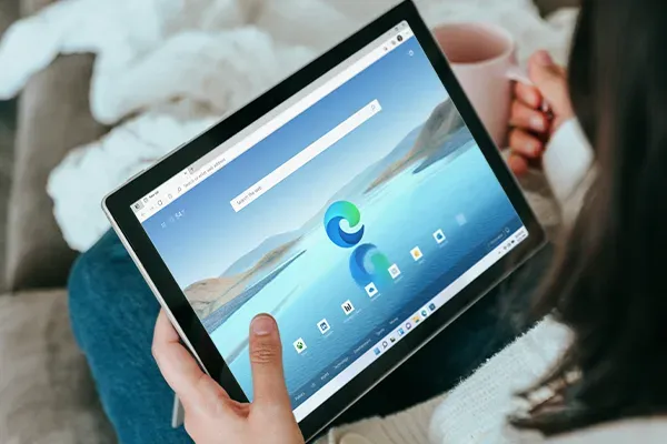 Woman holding tablet in left hand with a mug in the right