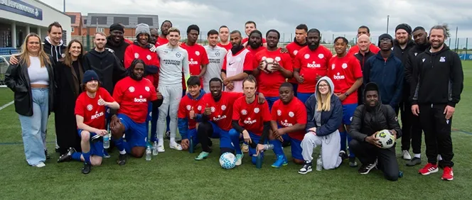 Group of people posing for a photo on football pitch