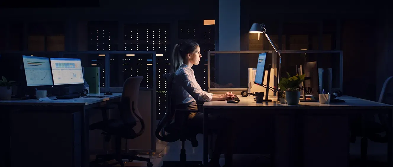 Woman in empty office looking at monitor and typing