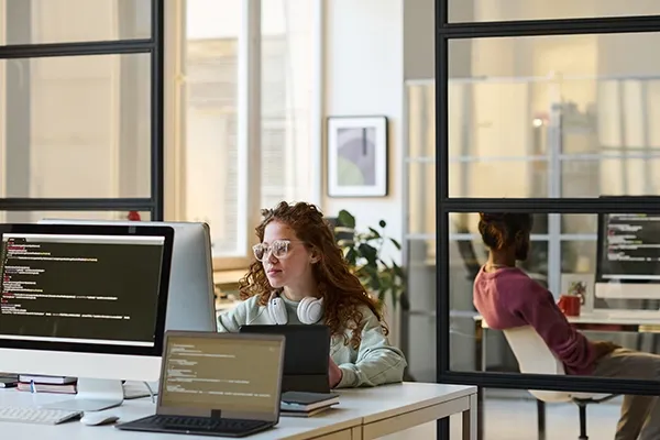Woman with glasses in an office looking at computer monitor