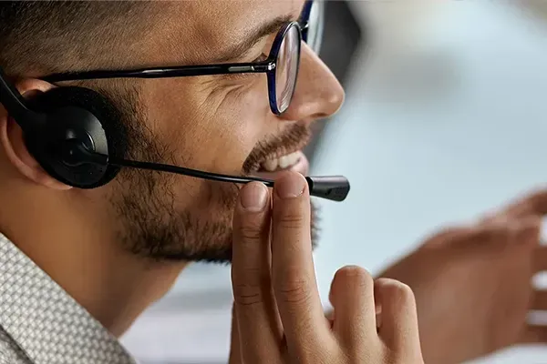 Man with glasses talking to someone with a headset