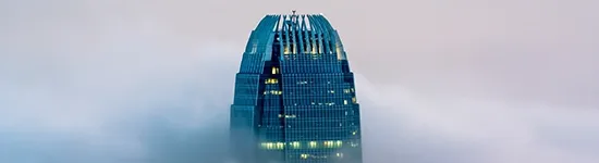 Glass skyscraper appearing above clouds