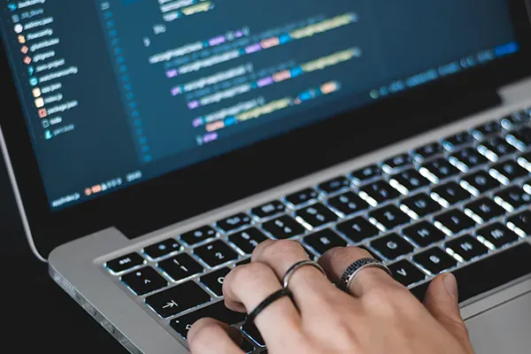 Person typing computer code on laptop