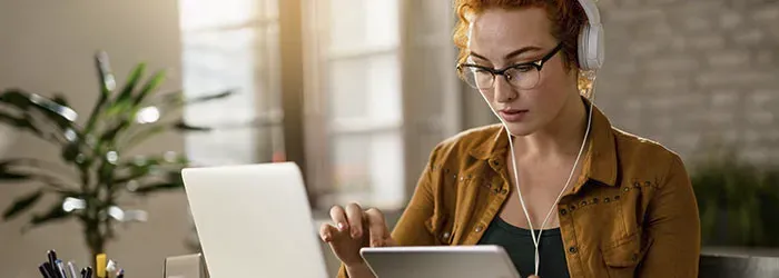 Woman with glasses and headphones on using tablet
