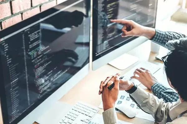 People looking at code on monitors