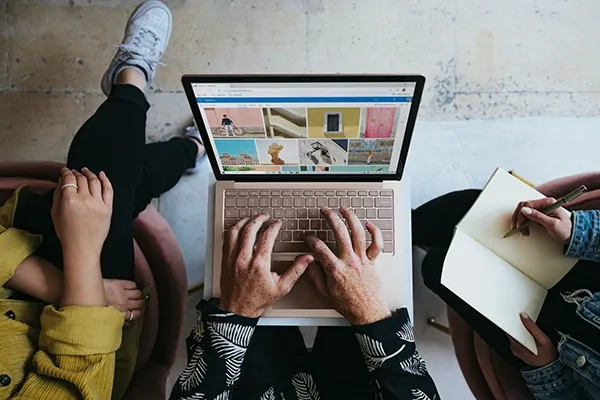 Person typing on laptop while two others sit either side