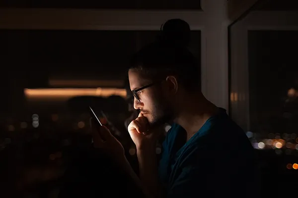 Man with glasses holding phone up to face